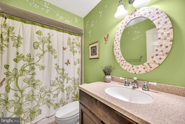 bathroom with curtained shower, vanity, and toilet