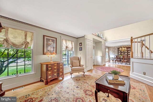 living room with light hardwood / wood-style flooring, a notable chandelier, and ornamental molding