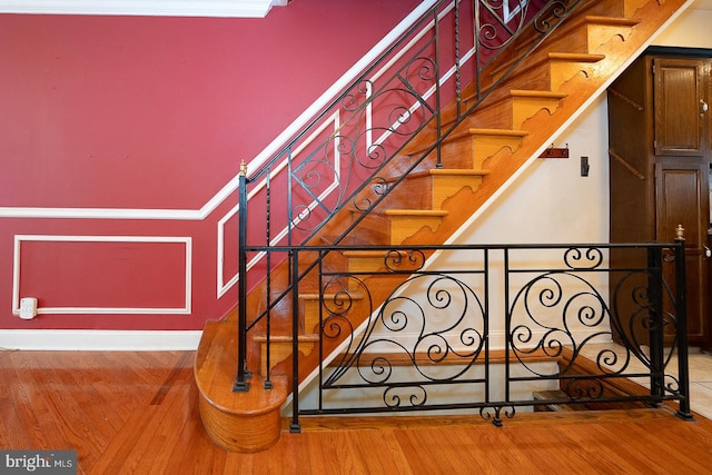 staircase featuring wood-type flooring and ornamental molding