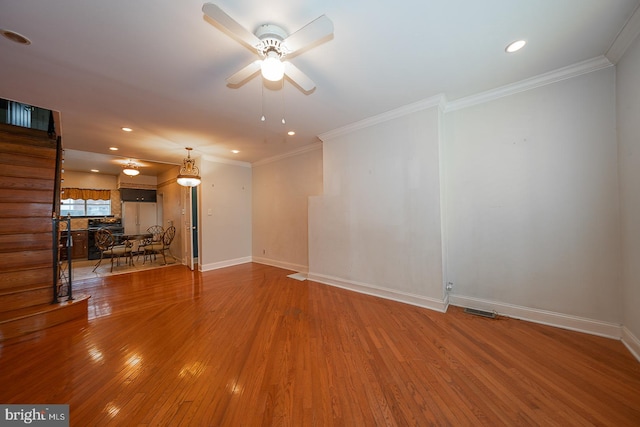 unfurnished living room featuring ceiling fan, hardwood / wood-style flooring, and ornamental molding