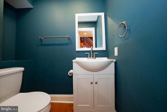 bathroom with wood-type flooring, vanity, and toilet