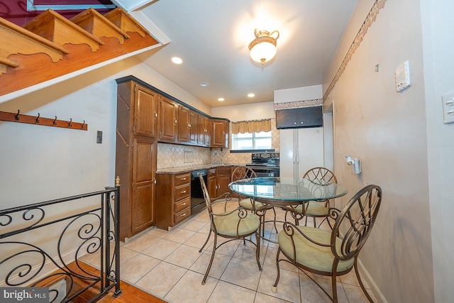 kitchen featuring decorative backsplash, light stone countertops, light tile patterned floors, black appliances, and sink