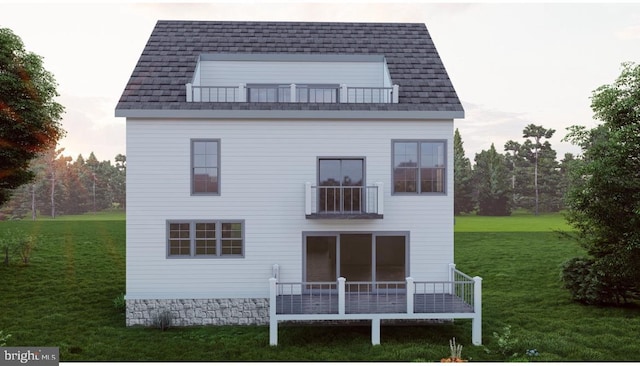 rear view of house featuring a lawn and a balcony