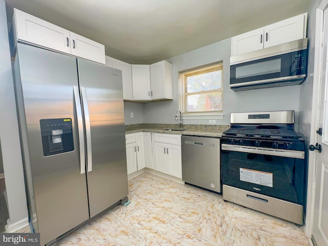 kitchen with light stone countertops, stainless steel appliances, sink, and white cabinetry