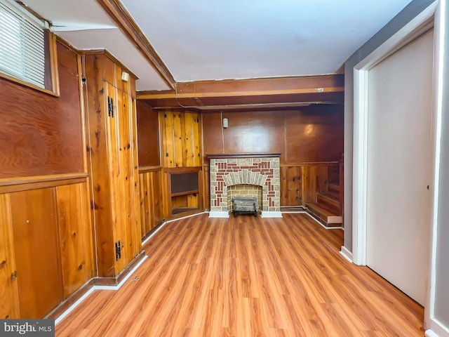 unfurnished living room featuring wooden walls, light hardwood / wood-style floors, and a fireplace