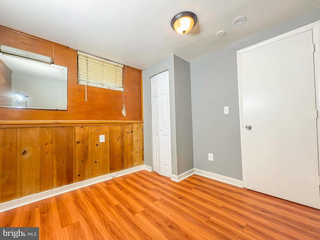 spare room featuring light hardwood / wood-style floors and wood walls