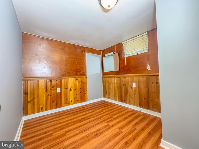 unfurnished room with wood walls and light hardwood / wood-style floors