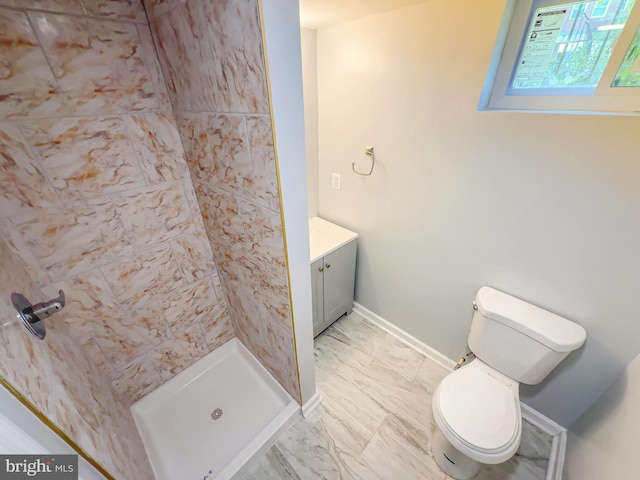 bathroom featuring vanity, a tile shower, and toilet