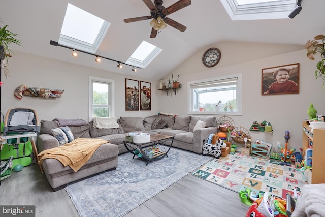 living room with vaulted ceiling with skylight, wood-type flooring, and ceiling fan