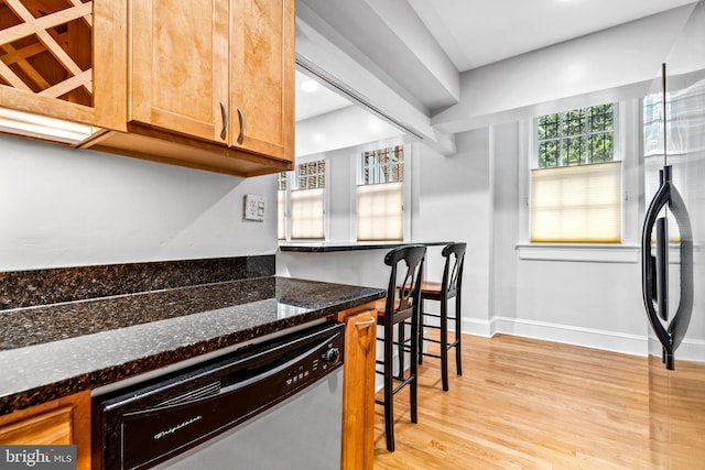 kitchen featuring appliances with stainless steel finishes, dark stone counters, and light hardwood / wood-style flooring