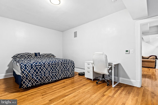 bedroom with light wood-type flooring and baseboard heating