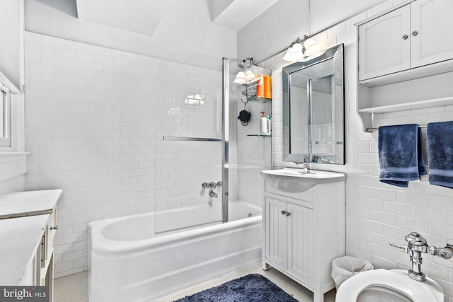 full bathroom with tile walls, tiled shower / bath, vanity, and toilet