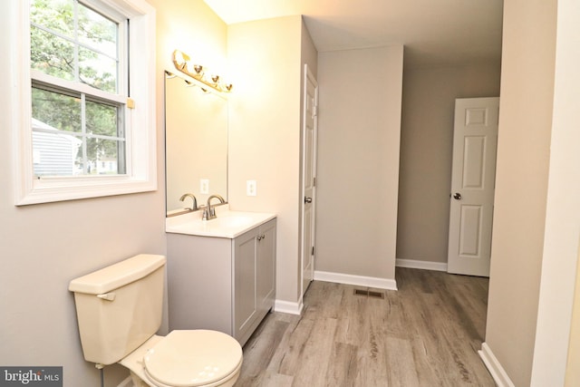 bathroom featuring hardwood / wood-style flooring, a wealth of natural light, toilet, and vanity