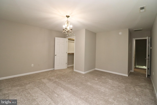 carpeted spare room with a notable chandelier