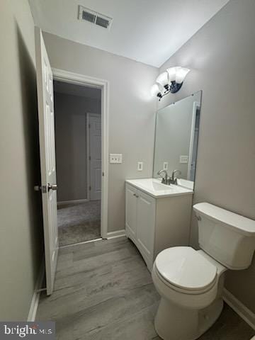 bathroom featuring toilet, hardwood / wood-style flooring, and vanity