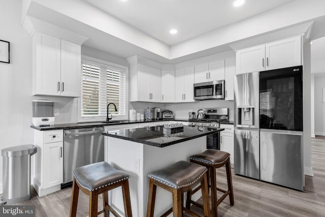 kitchen featuring appliances with stainless steel finishes, a breakfast bar, white cabinetry, and a sink