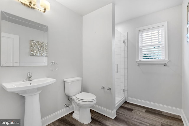 bathroom featuring hardwood / wood-style floors, toilet, and a tile shower