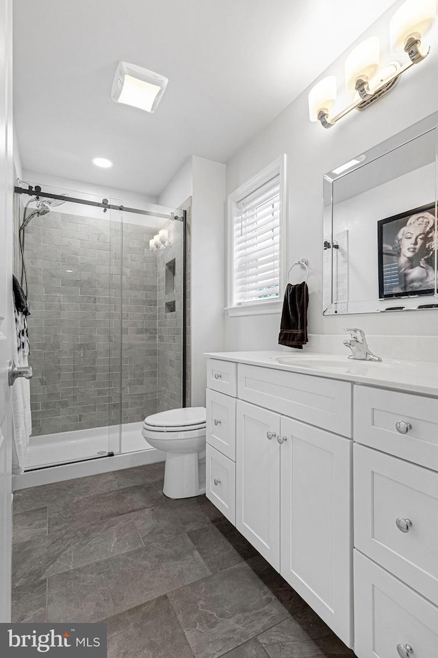 bathroom featuring toilet, vanity, and walk in shower