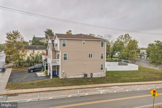 view of side of home featuring a yard, a balcony, and cooling unit