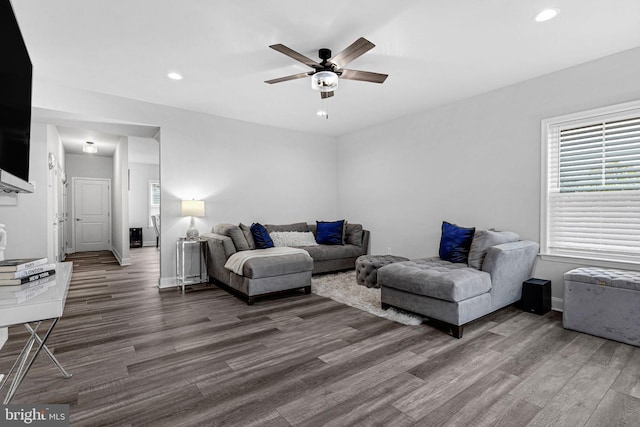 living room featuring ceiling fan and dark wood-type flooring