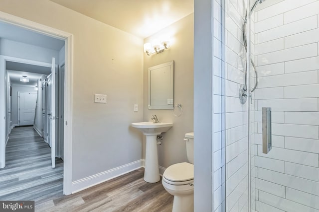 bathroom with wood-type flooring, toilet, and a shower with shower door