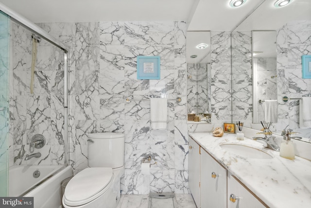 full bathroom with vanity, toilet, bath / shower combo with glass door, and tile walls