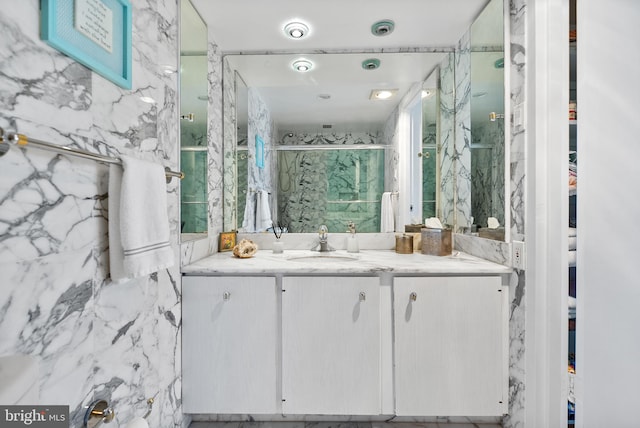 bathroom featuring a shower with door, vanity, and tile walls