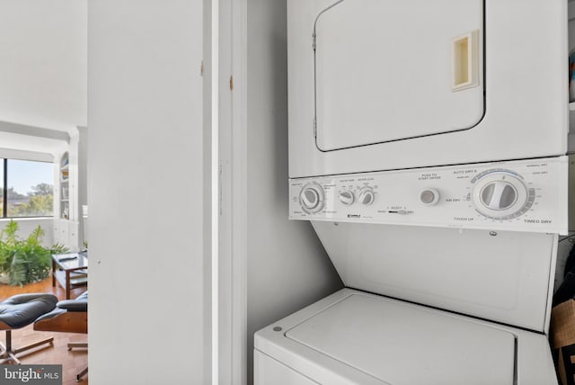 clothes washing area featuring hardwood / wood-style floors and stacked washer / dryer