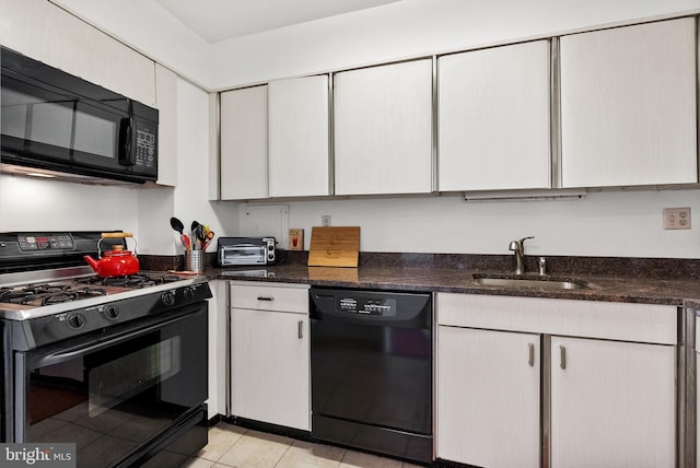 kitchen with dark stone counters, sink, light tile patterned floors, and black appliances