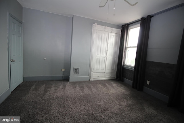 unfurnished room featuring dark colored carpet and ceiling fan