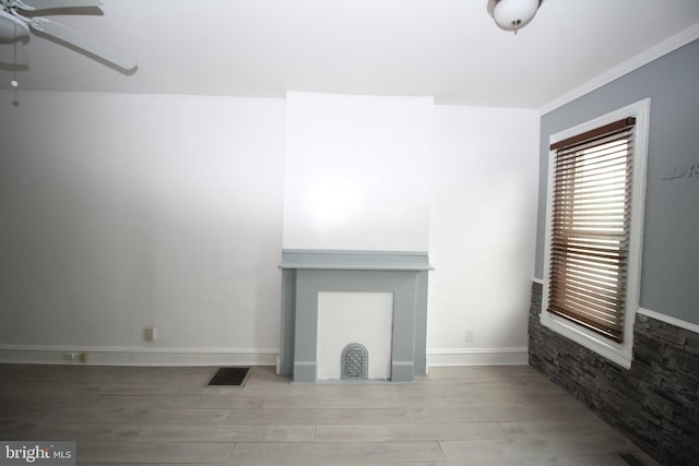 unfurnished living room with light wood-type flooring, ornamental molding, and ceiling fan