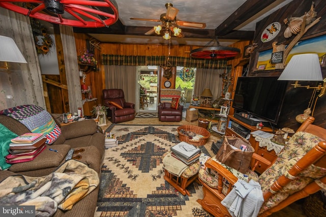 living room featuring wood walls, beam ceiling, and ceiling fan