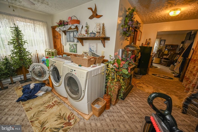 clothes washing area featuring a textured ceiling, a baseboard heating unit, washing machine and clothes dryer, and carpet floors