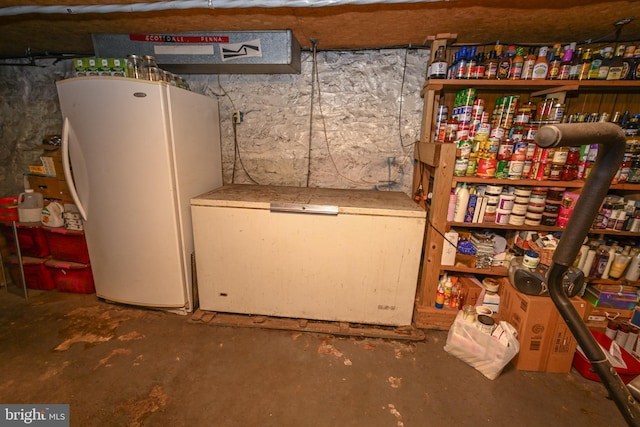 basement featuring water heater, white fridge, and refrigerator