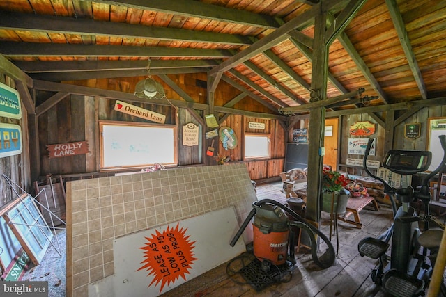 misc room with wooden walls, lofted ceiling with beams, wood ceiling, and a healthy amount of sunlight