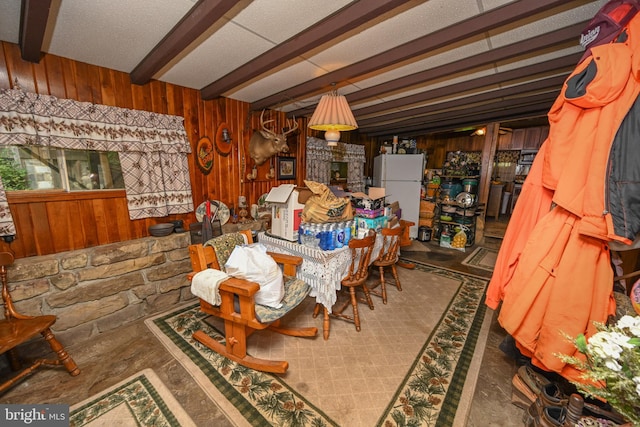 dining room featuring wood walls, beam ceiling, and a fireplace