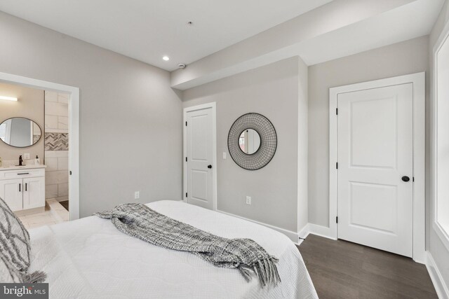 bedroom featuring ensuite bathroom and dark hardwood / wood-style flooring