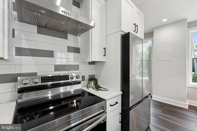 kitchen with light stone counters, white cabinetry, stainless steel appliances, range hood, and dark hardwood / wood-style flooring