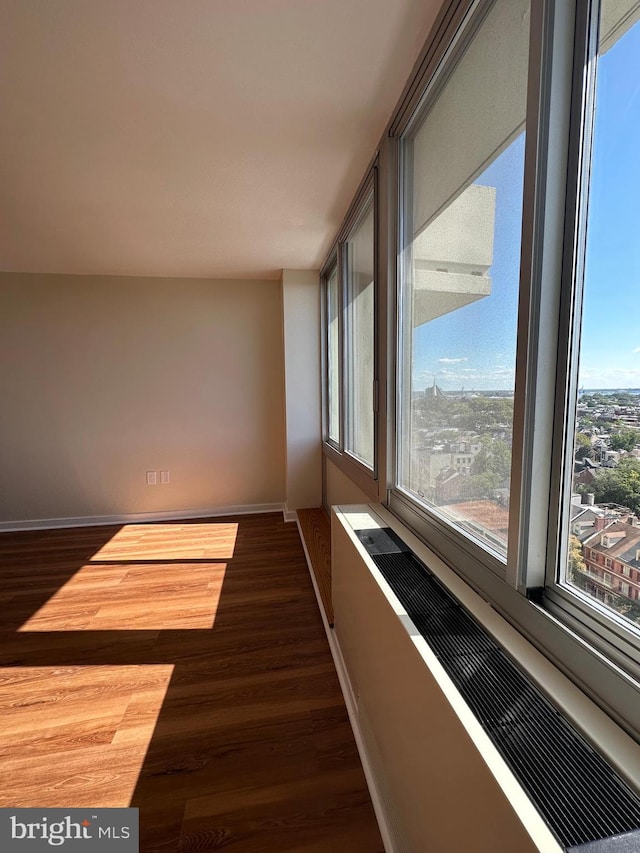 corridor featuring baseboards, radiator heating unit, and dark wood finished floors