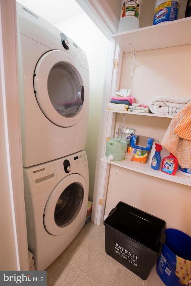 laundry area featuring stacked washer / drying machine and light tile patterned flooring