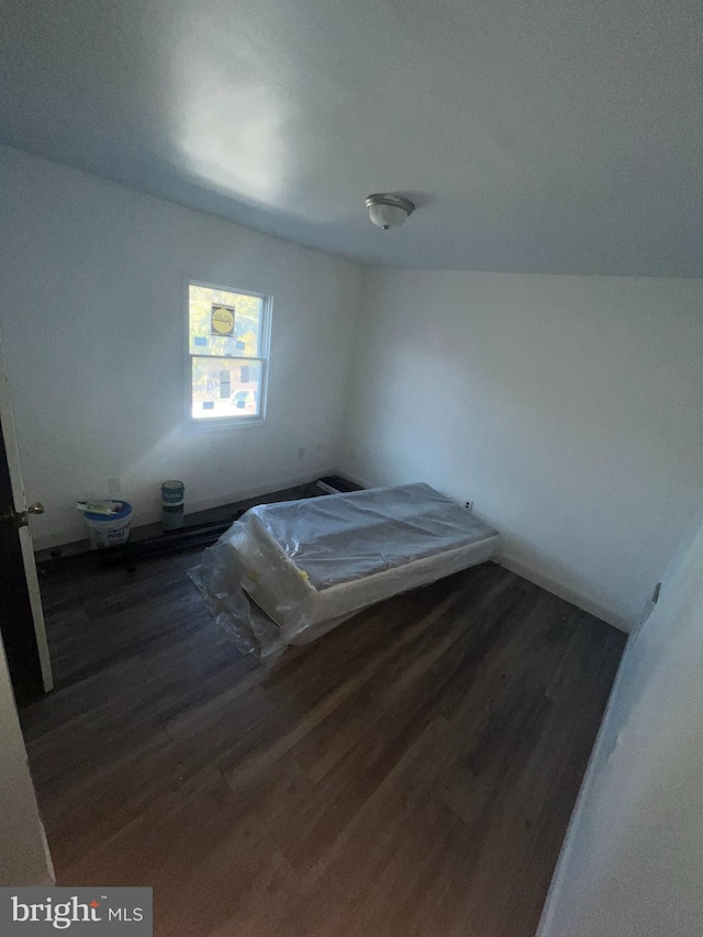 unfurnished bedroom featuring vaulted ceiling and dark hardwood / wood-style flooring