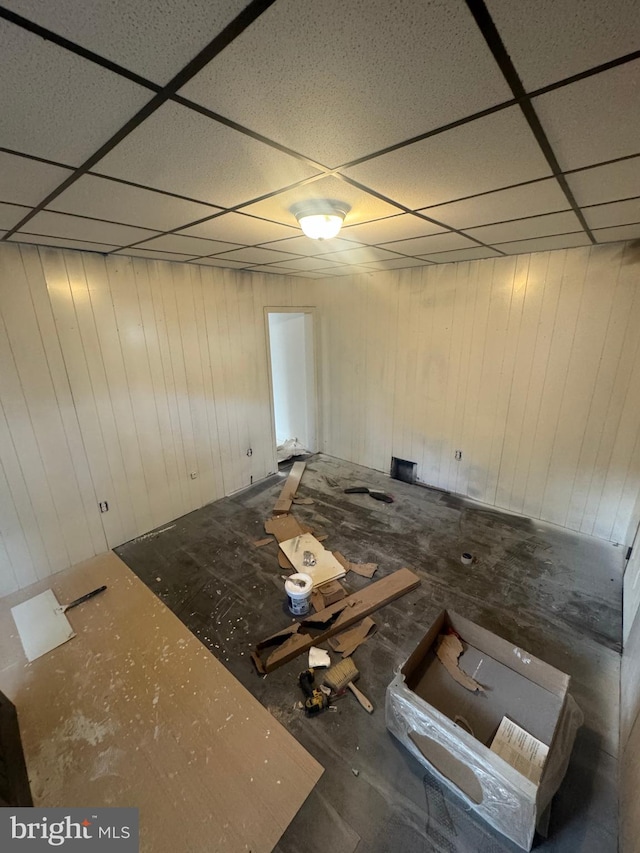 interior space featuring wooden walls and a drop ceiling