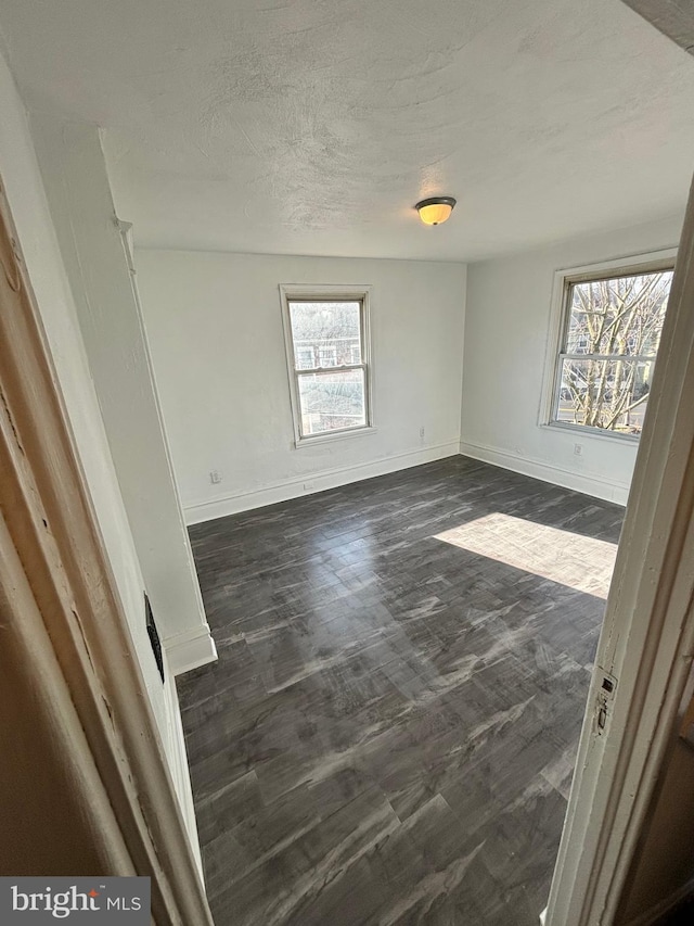 spare room with dark hardwood / wood-style floors and a healthy amount of sunlight