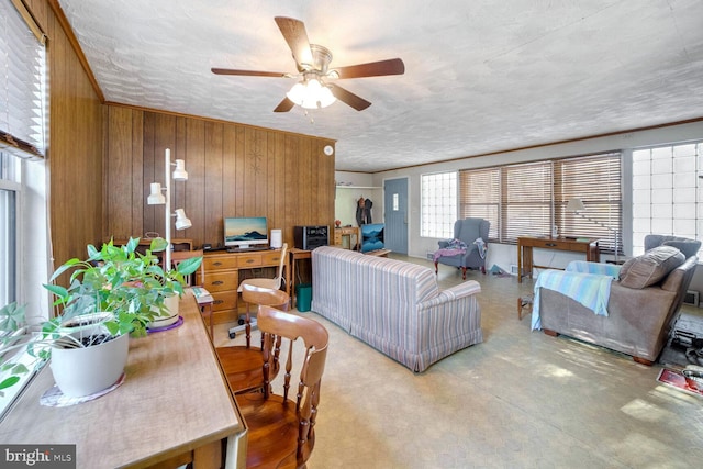 living room featuring ceiling fan, wooden walls, a textured ceiling, and concrete floors