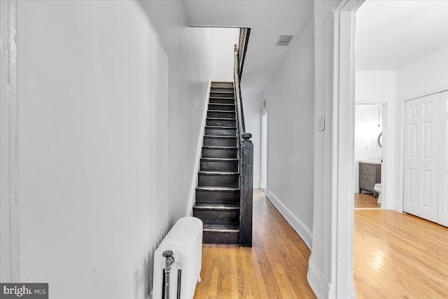 stairway with wood-type flooring and radiator