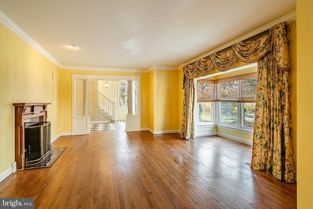 unfurnished living room with decorative columns, crown molding, and wood-type flooring