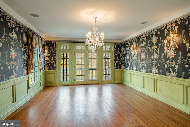 empty room with crown molding, a chandelier, and hardwood / wood-style flooring