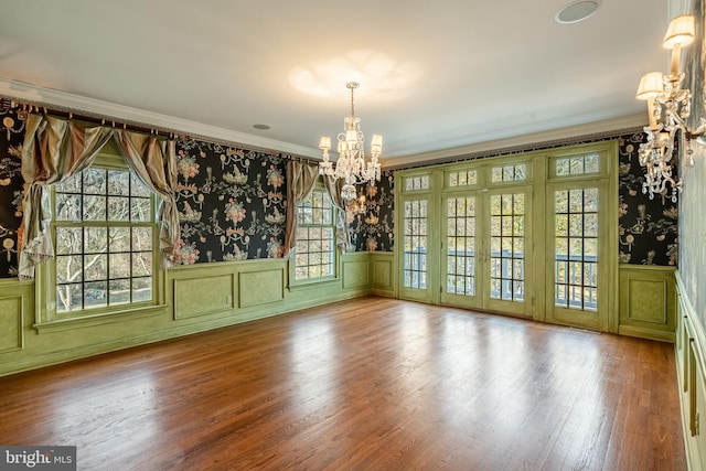 unfurnished dining area with ornamental molding, a chandelier, and hardwood / wood-style flooring