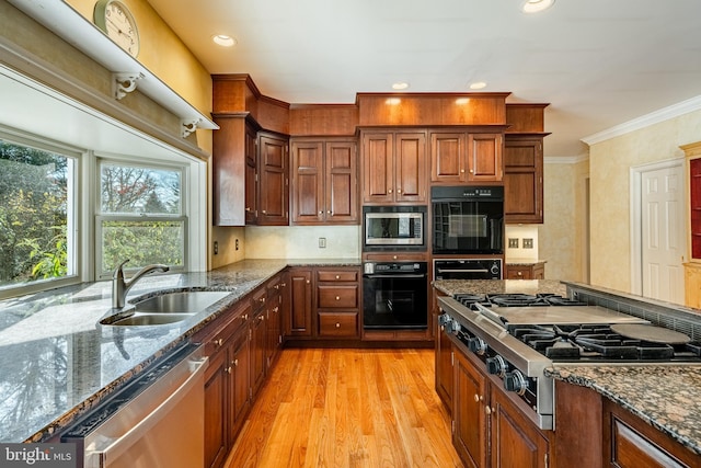 kitchen featuring dark stone countertops, stainless steel appliances, light hardwood / wood-style floors, and sink