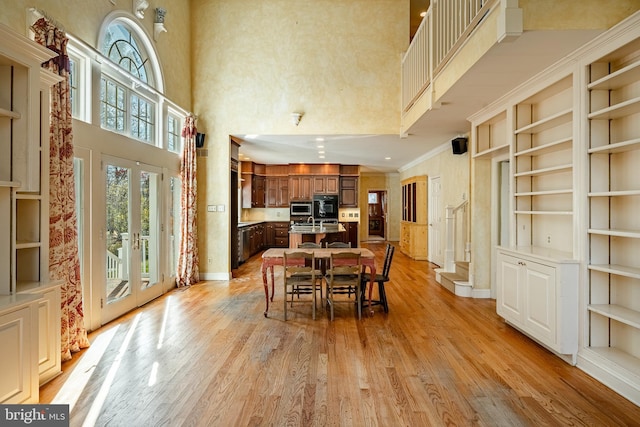 dining space featuring french doors, a high ceiling, built in features, light hardwood / wood-style floors, and ornamental molding